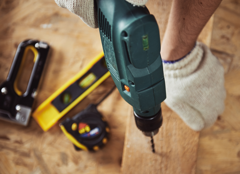 worker using a drill in wood. 