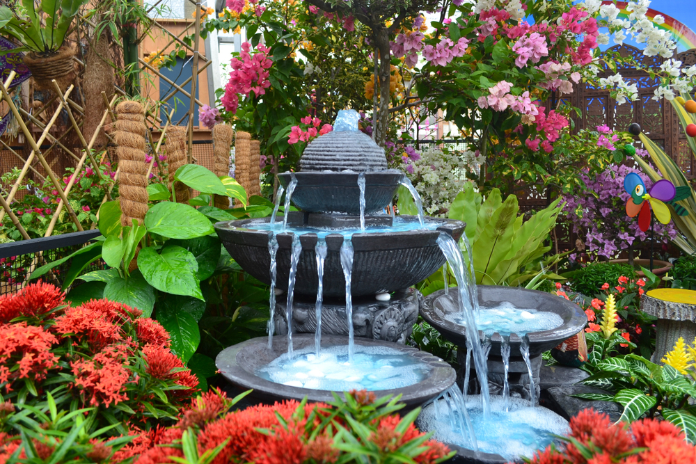 backyard fountain surrounded by flowers and plants